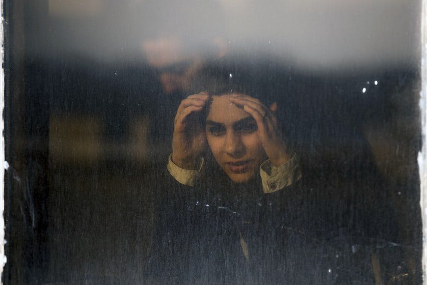 A woman in emotional pain with her hands holding her head.