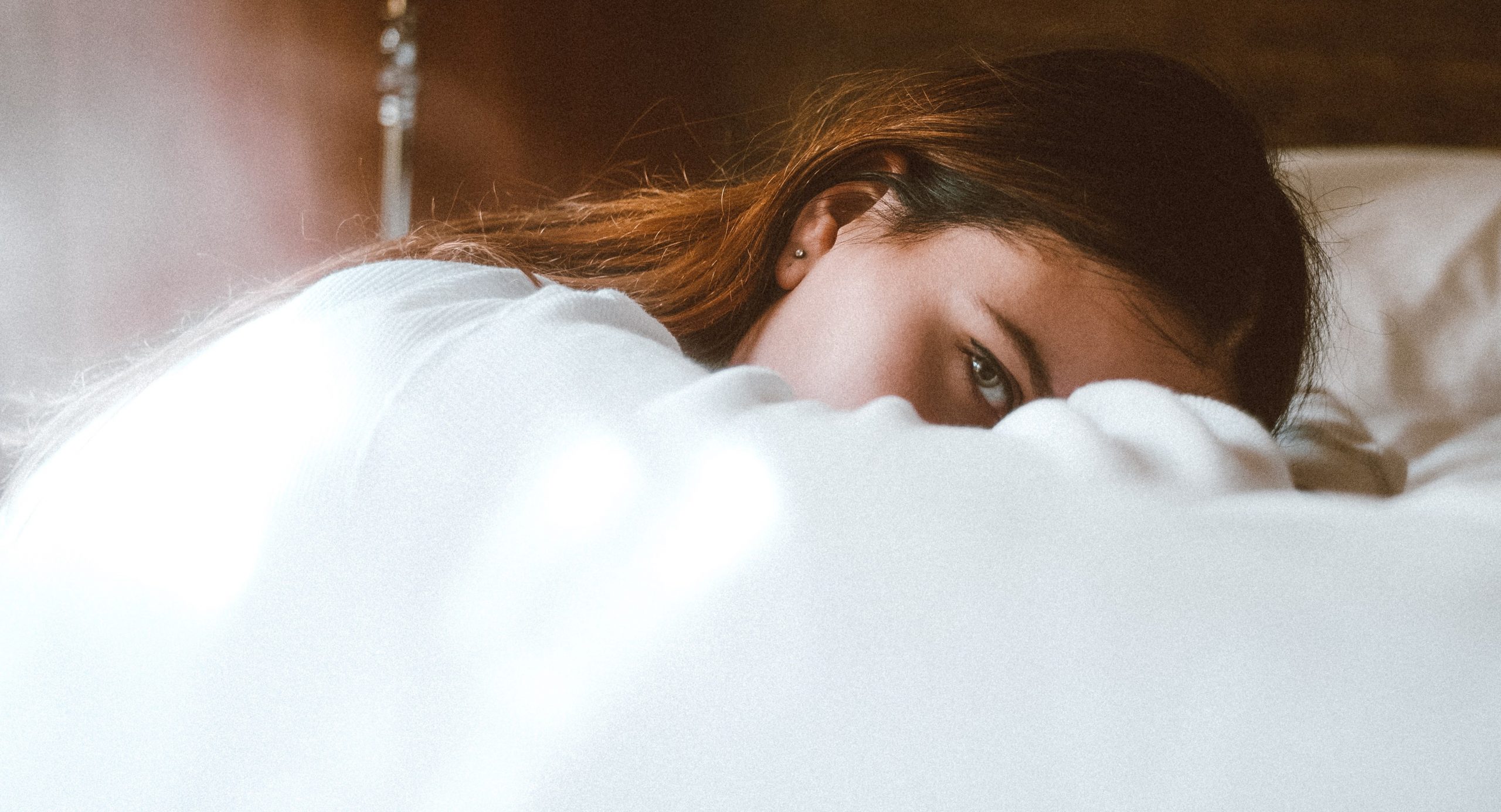 A woman with one eye open while still in bed